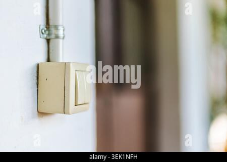 Vintage wall mounted light switch with exposed electrical conduit in rustic building interior Stock Photo