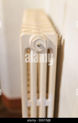 Close up view of vintage cast iron radiator with heating valve in traditional home interior Stock Photo