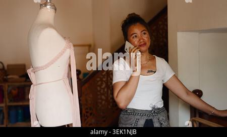 Asian woman discussing macrame design on phone, managing small creative business Stock Photo