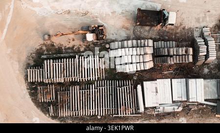 Construction site aerial view showing excavator, dump truck, and building materials Stock Photo