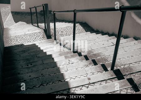 Sunlit stone staircase with sharp shadows and black railings, Belém, Lisbon, mood shot Stock Photo