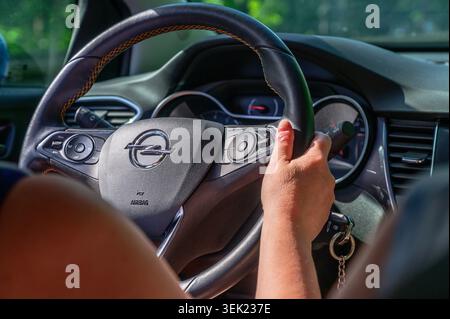 Augsburg, Germany — May 31 2026: Close up view of a driver's hand holding an Opel steering wheel with the corporate logo inside a vehicle cabin. Stock Photo