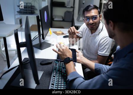 Software Developers Discussing AI Code On Computers In Tech Office Stock Photo