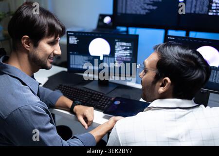 Software Developers Discussing AI Code On Computers In Tech Office Stock Photo