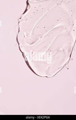 Cosmetic gel creating a textured smudge on a soft pink surface. Refreshing skincare product for beauty and health Stock Photo