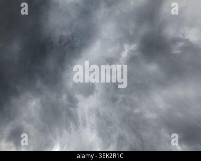 A wide view captures heavy, dark storm clouds gathering in the sky over Kyrgyzstan. The image showcases the turbulent texture and varying shades of gray within the cloud formations, evoking a sense of impending atmospheric change. Stock Photo