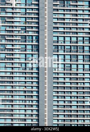 Urban skyscraper facade featuring glass windows and many balconies creating a geometric pattern Stock Photo