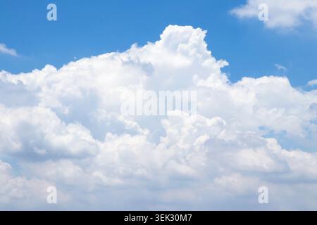 A bright blue sky with large cumulus clouds floating peacefully. Perfect for backgrounds, weather concepts, nature themes, and environmental visuals. Stock Photo