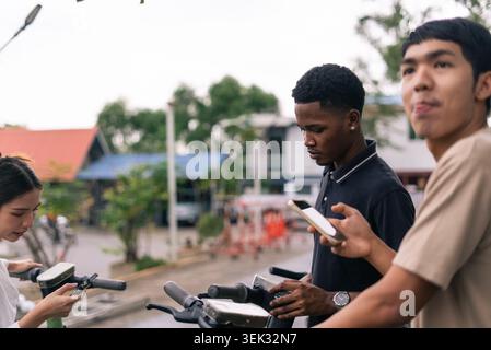 Young diverse people using smartphones with shared electric scooters, urban mobility Stock Photo