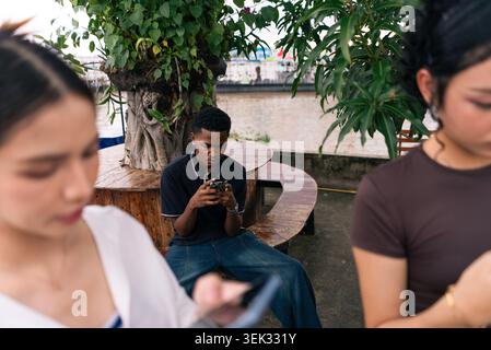 Young people immersed in smartphone screens, disconnecting socially in urban setting Stock Photo