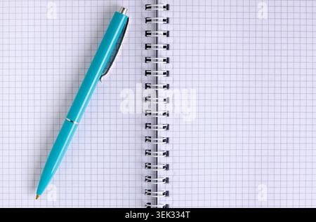 Close up view blue ballpoint pen lying diagonally on pages an open spiral notebook Stock Photo