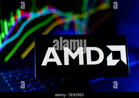 AMD Logo Displayed On Mobile Phone With Stock Market Performance Chart Background And Trading Graph Interface Stock Photo