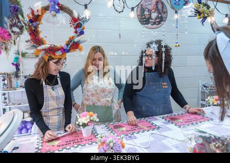 Women concentrating on making decorative items and crafts together at a festive market stall Stock Photo