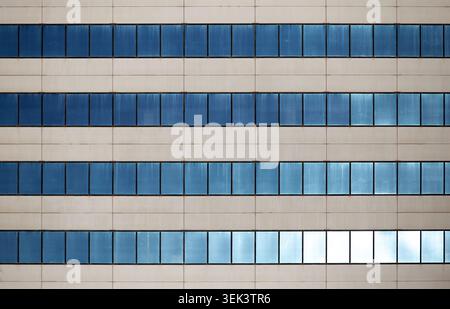 Modern office building facade with repetitive blue windows pattern Stock Photo