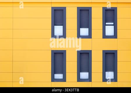 Yellow modern building facade with repetitive windows and geometric pattern Stock Photo