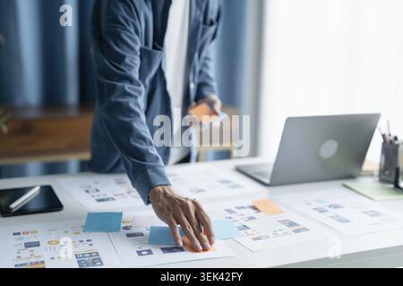 UX UI designer plans innovative mobile app with paper wireframe designs in the workspace Stock Photo