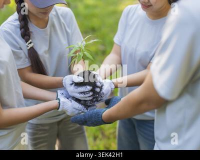 Group of Asian people holding seeds and standing in a circle in the forest Stock Photo
