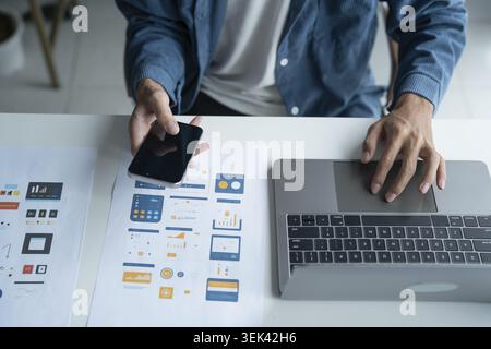 UX UI designer plans innovative mobile app with paper wireframe designs in the workspace Stock Photo