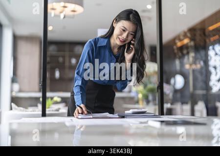 Beautiful confident Asian secretary, clever, professional businesswoman talking on the phone in office Stock Photo