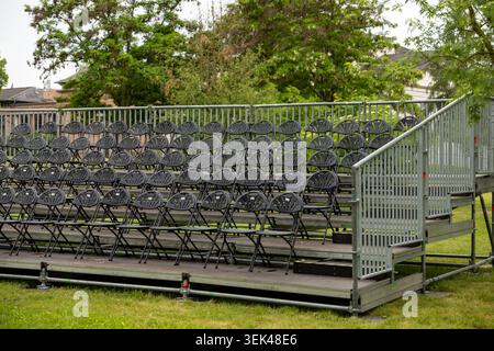 Empty outdoor spectator grandstand with rows of folding chairs at event venue Stock Photo
