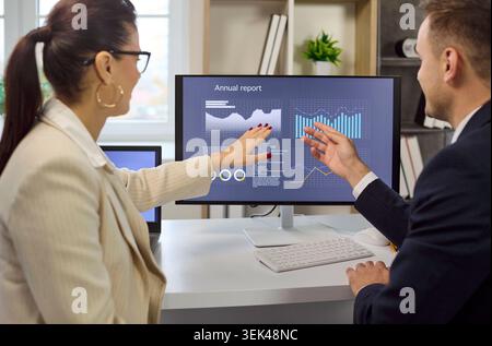 Colleagues pointing at financial charts on analytics dashboard in office meeting Stock Photo