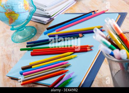 Multicolored pencils on table with papers and notebooks Stock Photo