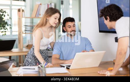 Engaged man and women reviewing corporate strategy during productive teamwork session in contemporary studio Stock Photo