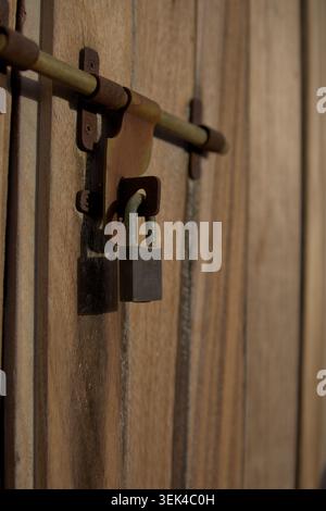 Old Brass Padlock and Sliding Latch on Weathered Wooden Door Macro Shot of Antique Rusty Lock on Traditional Timber Gate Stock Photo