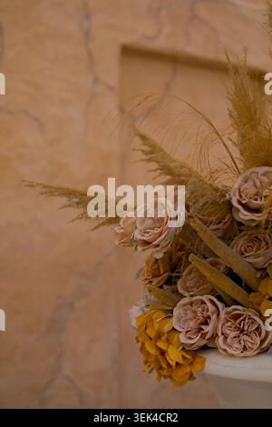 Earthy Tone Flower Bouquet Against Textured Adobe Wall Muted Rose and Dried Pampas Grass Floral Arrangement Stock Photo