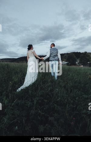Couple walks hand-in-hand through tall grass Stock Photo