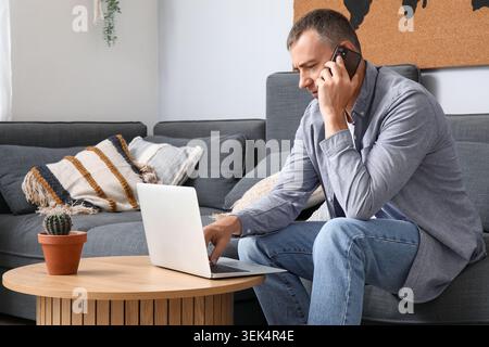 Mature male freelancer talking by mobile phone on sofa at home Stock Photo