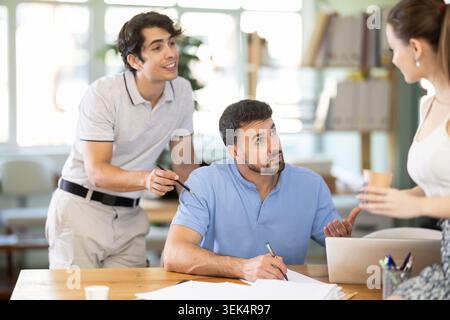Colleagues work on paper drawing, making sketches while discussing construction plan in office Stock Photo