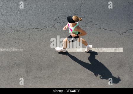 Top down view of a woman running on an asphalt road during a marathon Stock Photo