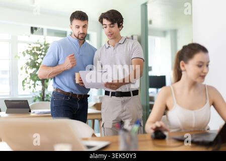 Two businessmen at office discuss financial data project documents paperwork Stock Photo