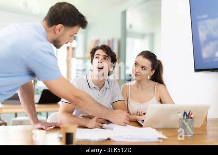 Colleagues work on paper drawing, making sketches while discussing construction plan in office Stock Photo