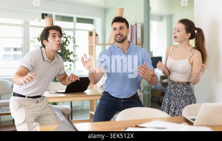 Office workers balancing cups on head enjoying their break time Stock Photo