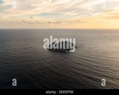 Aerial view of a small tropical island with dense forest and white ...