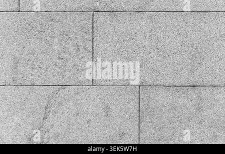 Close-up of a gray granite wall made of rectangular stone blocks showing fine grain, seams and subtle weathering; a clean architectural surface ideal Stock Photo
