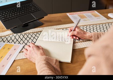 Middle Aged Woman Taking Notes during Online Skills Training Stock Photo