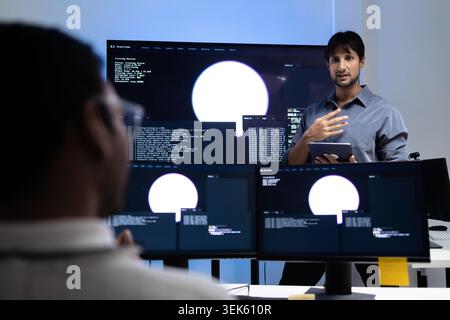 Young Programming Instructor Teaching AI Training Lesson In Tech Office Stock Photo