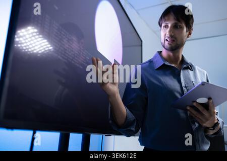 Latin Programming Instructor Teaching AI Training With Tablet In Tech Office Stock Photo