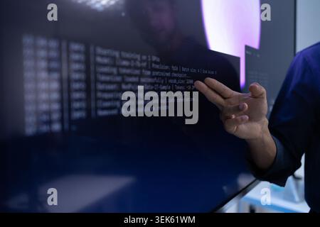 Hand Pointing At AI Training Code On Digital Screen Stock Photo