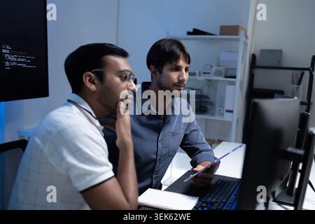 Focused Software Developers Working Together At Computer In Tech Office Stock Photo
