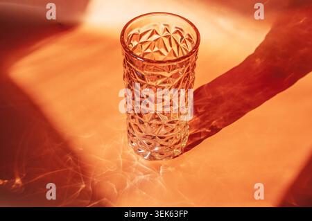 Textured glass vase casting dramatic shadows on an orange background Stock Photo