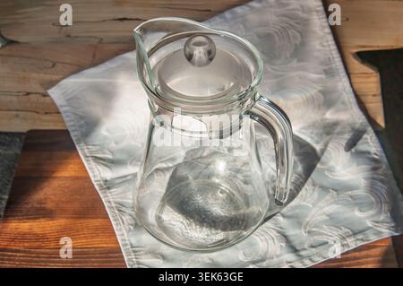 Elegant glass pitcher with lid resting on a patterned cloth Stock Photo