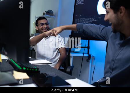 Software Developers Celebrating Success With Fist Bump In Tech Office Stock Photo