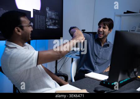 Software Developers Celebrating Success With Fist Bump In Tech Office Stock Photo