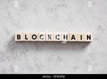 Blockchain word spelled out using wooden alphabet cubes on a concrete, textured surface, representing decentralized finance Stock Photo