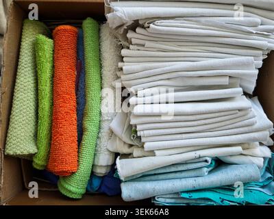 A cardboard box contains various cleaning cloths in different colors, used for household tasks and repairs in an apartment. Stock Photo