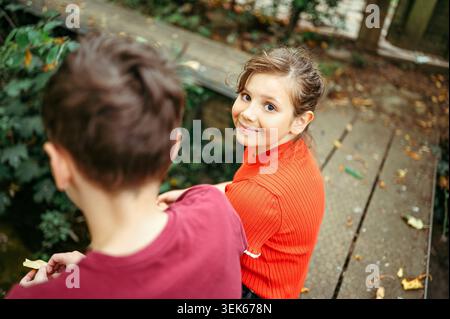 Smiling child girl looking back to camera while sitting in woodland Stock Photo